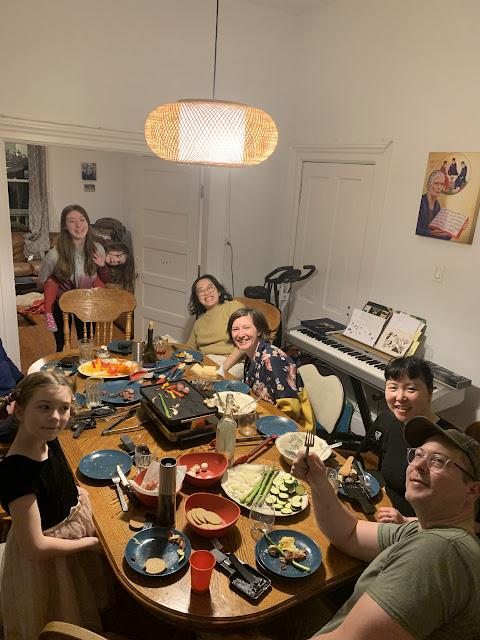 A full table of adults and children sharing a raclette dinner
